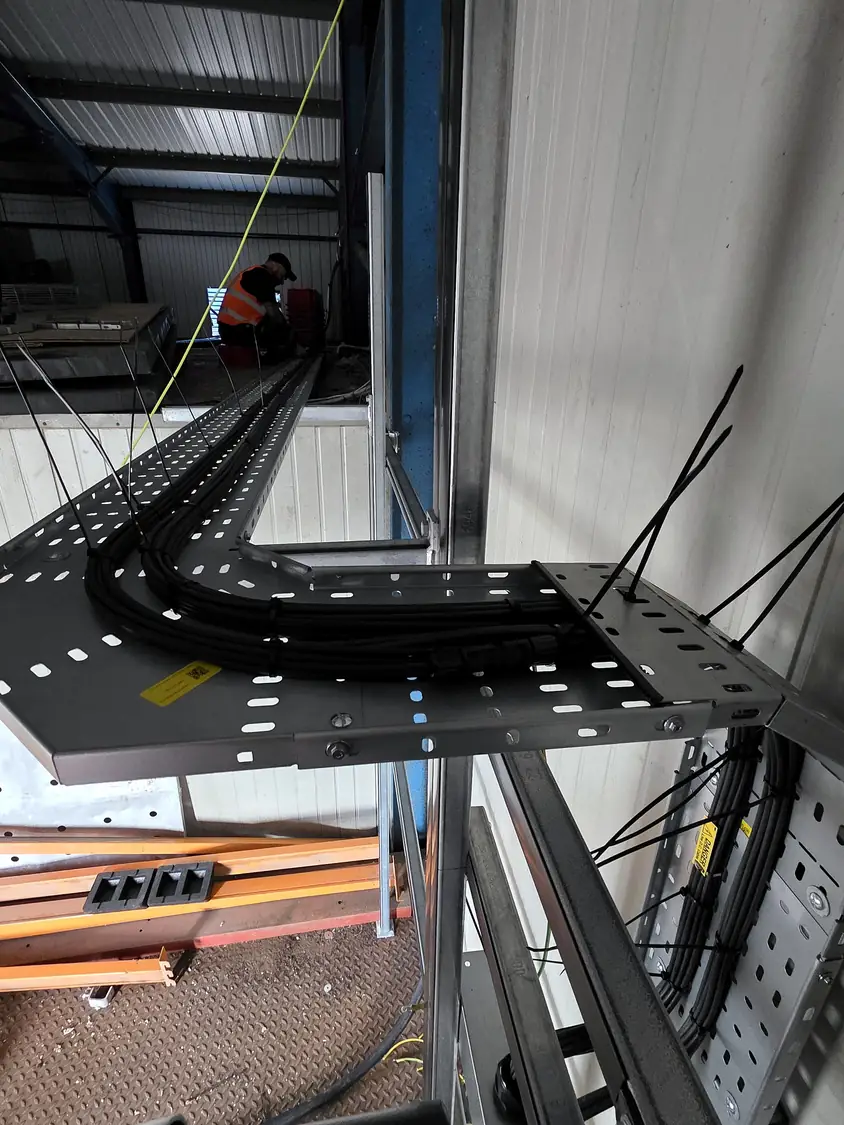 Cable tray run inside the building, with an operative working in the background